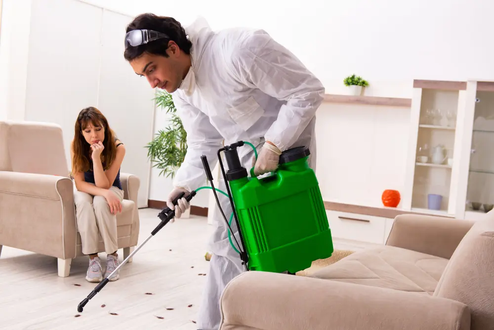 Technician performing pest control before moving into new home while homeowner watches.